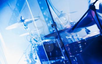 Blue toned musical photo background, rock drum set behind glass wall with cymbals