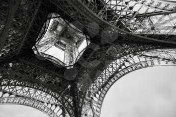 Looking up inside of the Eiffel tower, the most popular landmark of Paris, France. Monochrome photo with retro style effect