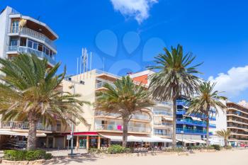 Modern buildings and palm trees on main coastal street of Calafell resort town in sunny summer day. Tarragona region, Catalonia, Spain