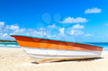 Orange and white pleasure boat lays on sand of Macao Beach, coastal landscape. Dominican Republic, Hispaniola Island