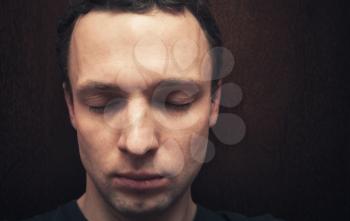 Young Caucasian man with closed eyes. Studio portrait over dark wall background