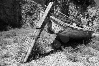 Old abandoned dry wooden fishing boat lays on the ground. Black and white photo