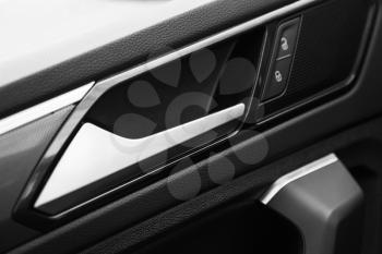 Inner door handle with lock unlock buttons, modern black car interior detail