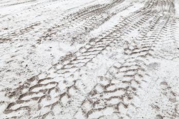 Tractor tire tracks pattern on sandy white ground in winter, abstract transportation background photo with selective focus