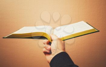 Male hand holds open book, vintage toned photo with selective focus