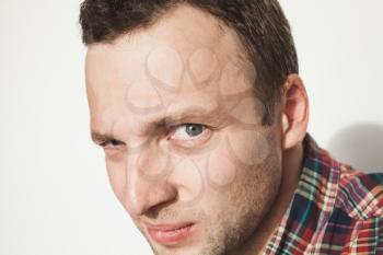 Young adult Caucasian man in colorful casual shirt over white wall looks closely at the camera