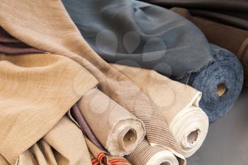 Rolls of natural linen cloth lie on the market counter
