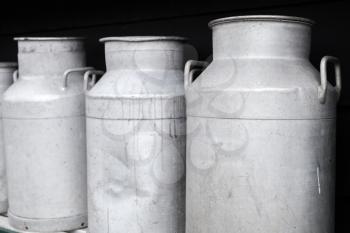 Metal milk churns stand in a row, close up photo