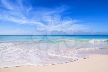 Tropical beach background, white sand, azure shore water under cloudy blue sky. Caribbean Sea coast, Dominican republic, Saona island