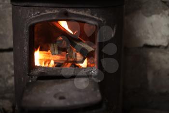 Fire burning in small black iron stove. Closeup photo with selective focus