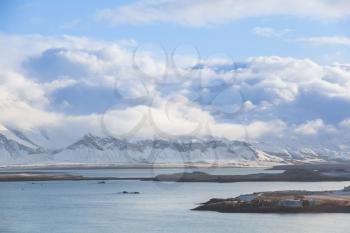 Coastal Icelandic landscape with snowy mountains under cloudy sky. Reykjavik bay, Iceland