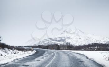 Icelandic road covered with snow, rural landscape with mountains on horizon