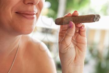 Young smiling European woman smokes handmade cigar, closeup photo with selective focus. Dominican Republic