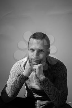 Vertical black and white portrait of sitting young adult European man