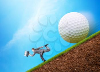Businessman runs from a big golf ball