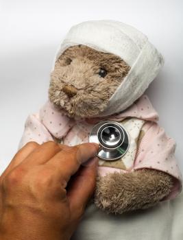 Medical examination of ill teddy bear in bed