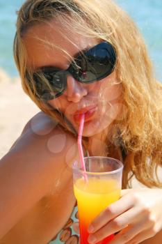Beautiful young girl with cocktail on the beach