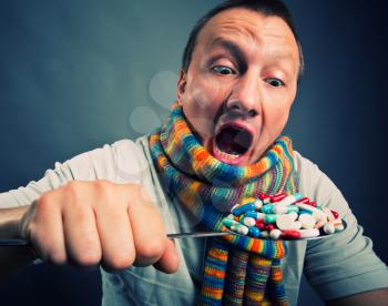 Man eating pills and medicines with big spoon