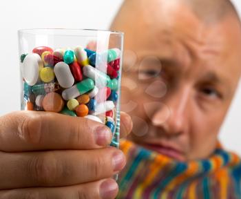 Sad man drinking cocktail of colorful pills