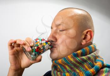 Ill man drinking cocktail of colorful pills