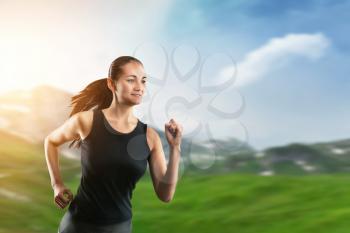 Sport woman running on green grass on blue sky background