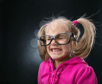 Scared little girl in funny big spectacles on grey