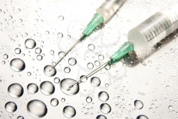 Two medical syringes and water drops