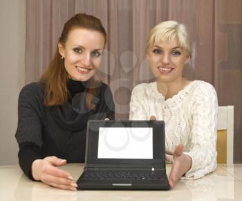 Two businesswomans showing a sign on laptop