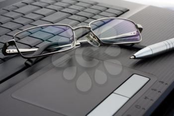 Businessman's glasses and pen on laptop computer