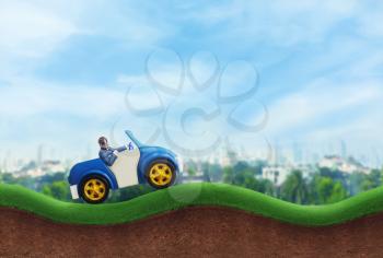Happy businessman driving a toy car on the hills