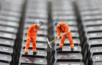 Small figurines of workers repairing computer keyboard