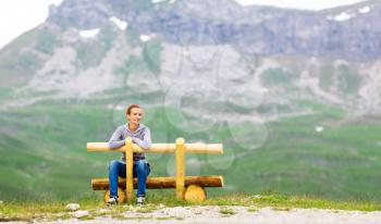 Mountain landscape and girl sitting on wooden bench. National Park in mountains of Montenegro, Europe