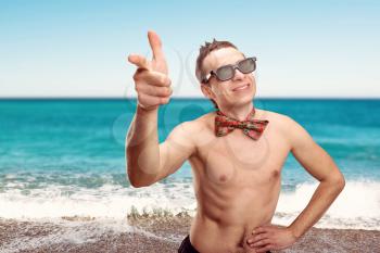 Happy womanizer pointing at you on the beach