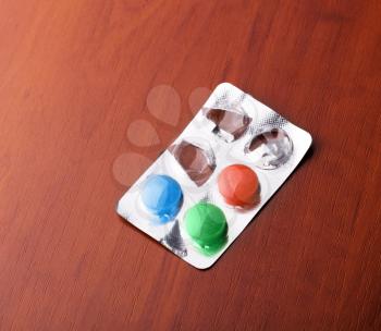 Pack with colorful pills on a wooden table