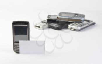 Mobile phone with contact business card and heap of phones in background
