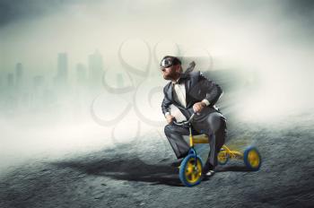 Odd businessman riding a small bicycle against dark city