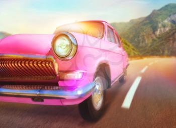 Pink retro car on the road in mountains 