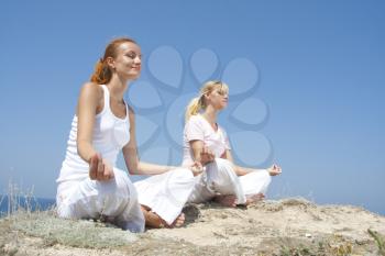 Two woman in white meditating in mountains