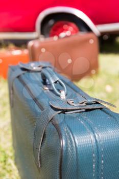 Suitcases standing on the grass near a red car