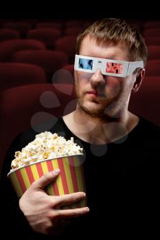 Portrait of man watching 3D movie and holding bucket of popcorn