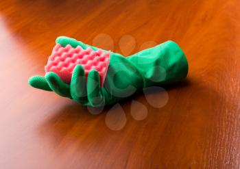 Green cleaning glove with a sponge on the wooden table