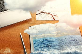 Office table in clouds with the sea on the notebook