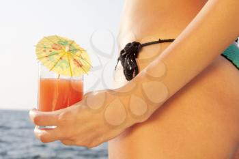 Tan woman with cocktail on the beach