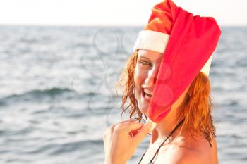 Tan smiling woman in christmas hat in sea