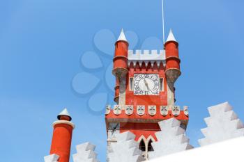 Red castle tower with clock against the clear sky
