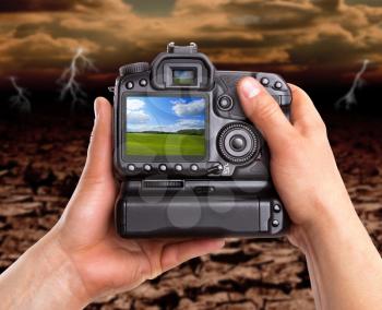 Hands holding digital camera and capturing beautiful landscape against dramatic area