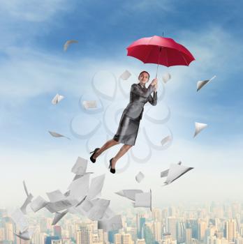 Businesswoman is flying on a red umbrella over downtown