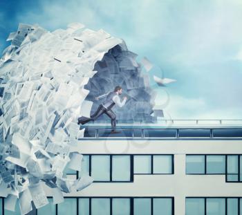 Businessman running from big wave of paperwork