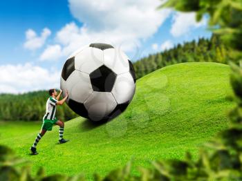 Football-player pushing a big ball on the hill 
