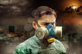 Young man in gas-mask in night town with atmospheric pollution
